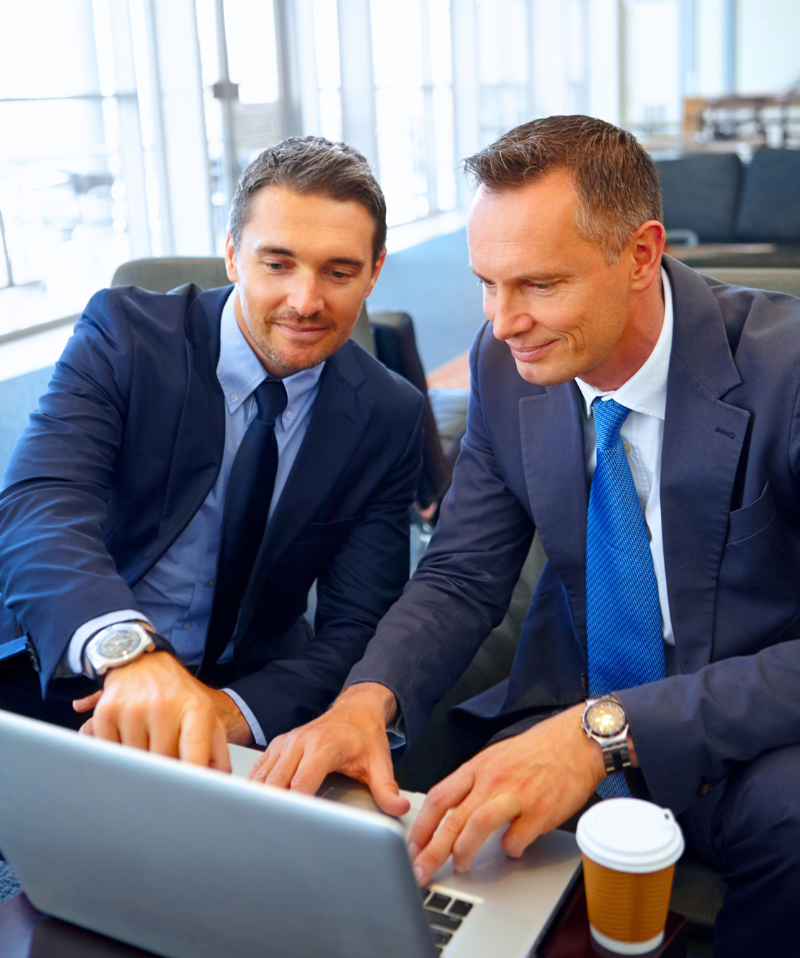 Two businessmen review a document on a laptop. Two businessmen review a document on a laptop.