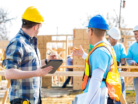 Two project managers review plans at a site build.