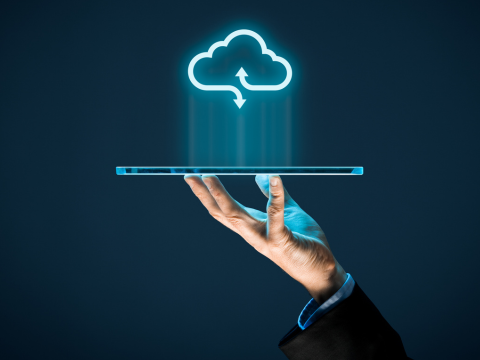 A person holds a laptop with an image of a cloud hovering over it to represent cloud computing.