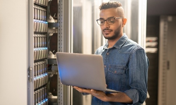 Man holding laptop in server room 
